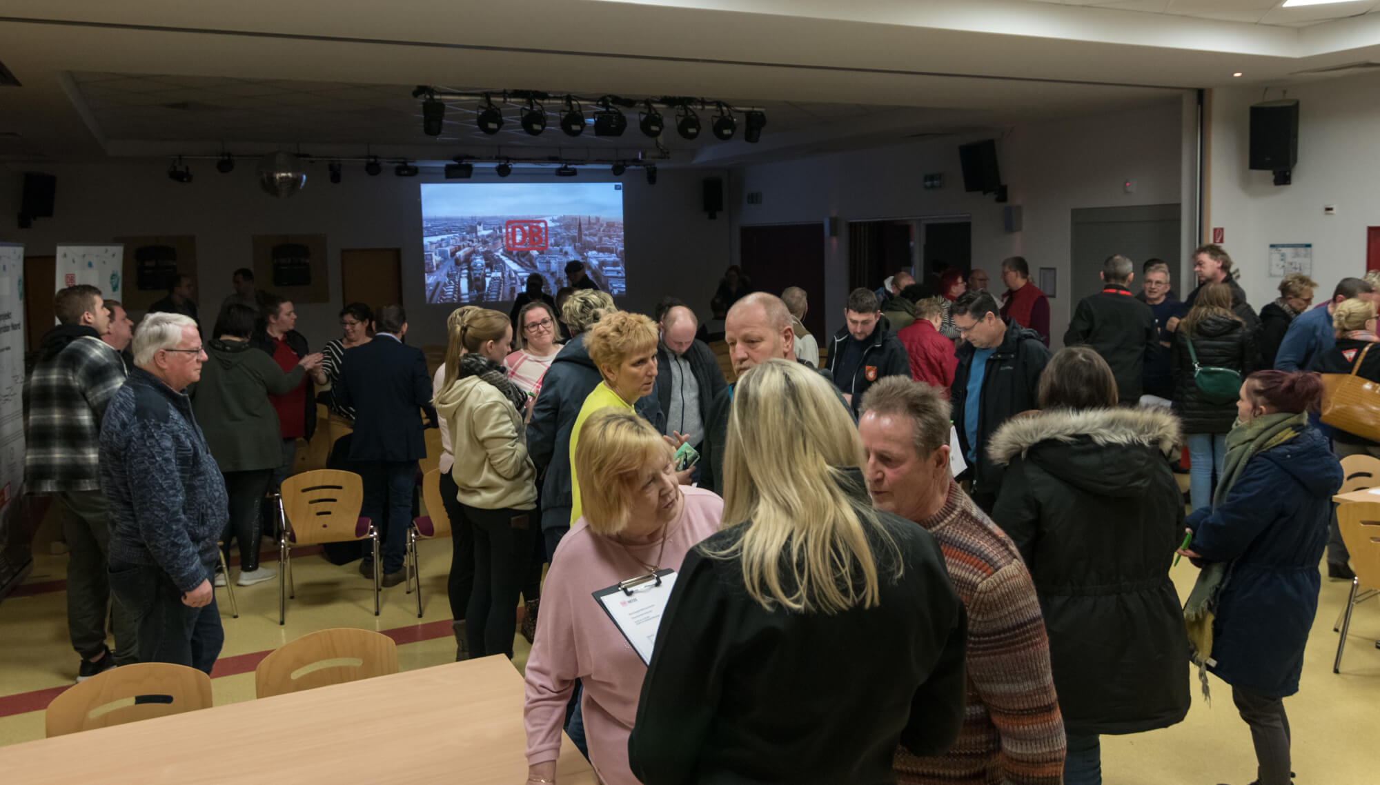 Bild zeigt eine Bürgerveranstaltung, ca. 20-30 Besucherinnen und Besucher, Präsentation auf Leinwand