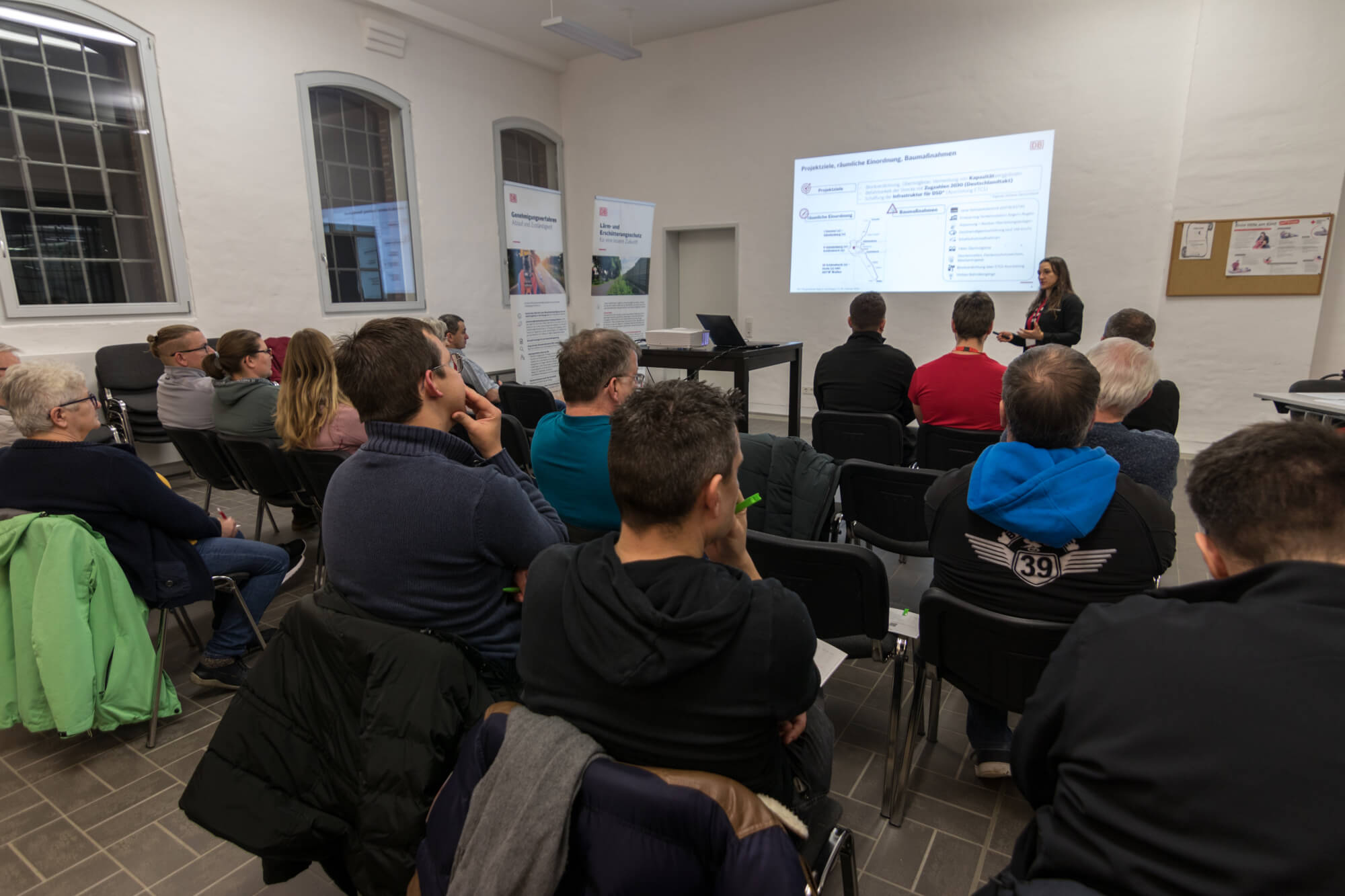 Bürgerveranstaltung, sitzendes Publikum, Präsentation auf Leinwand